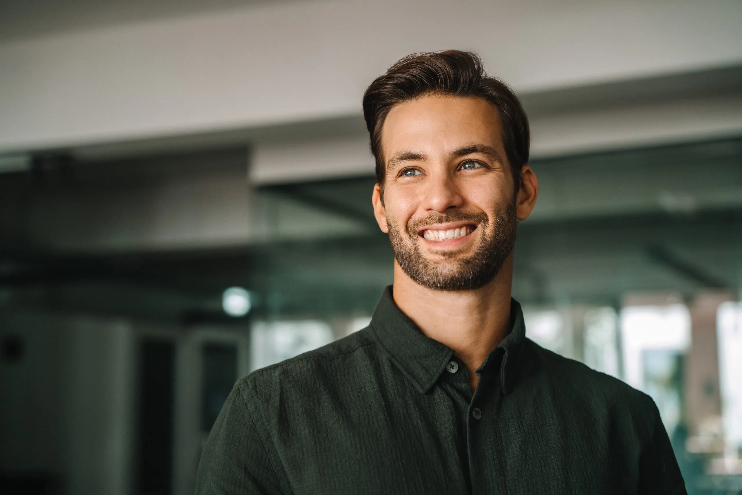 Smiling man in dark button-up shirt in a modern office interior