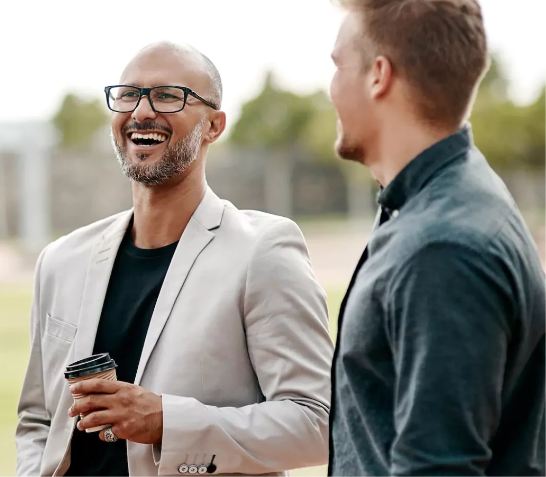 Two men having a friendly conversation and laughing outdoors