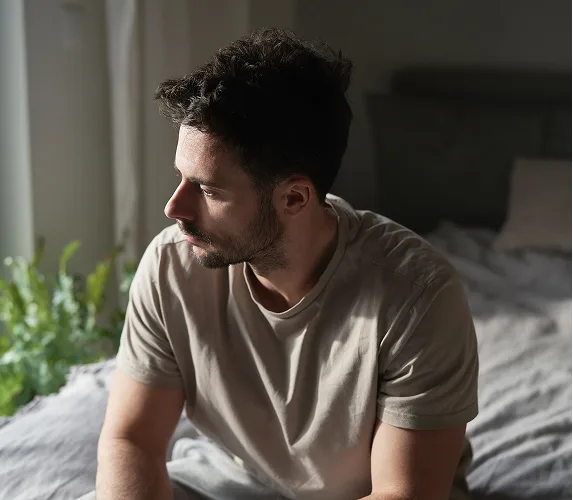 Man sitting on bed looking out window