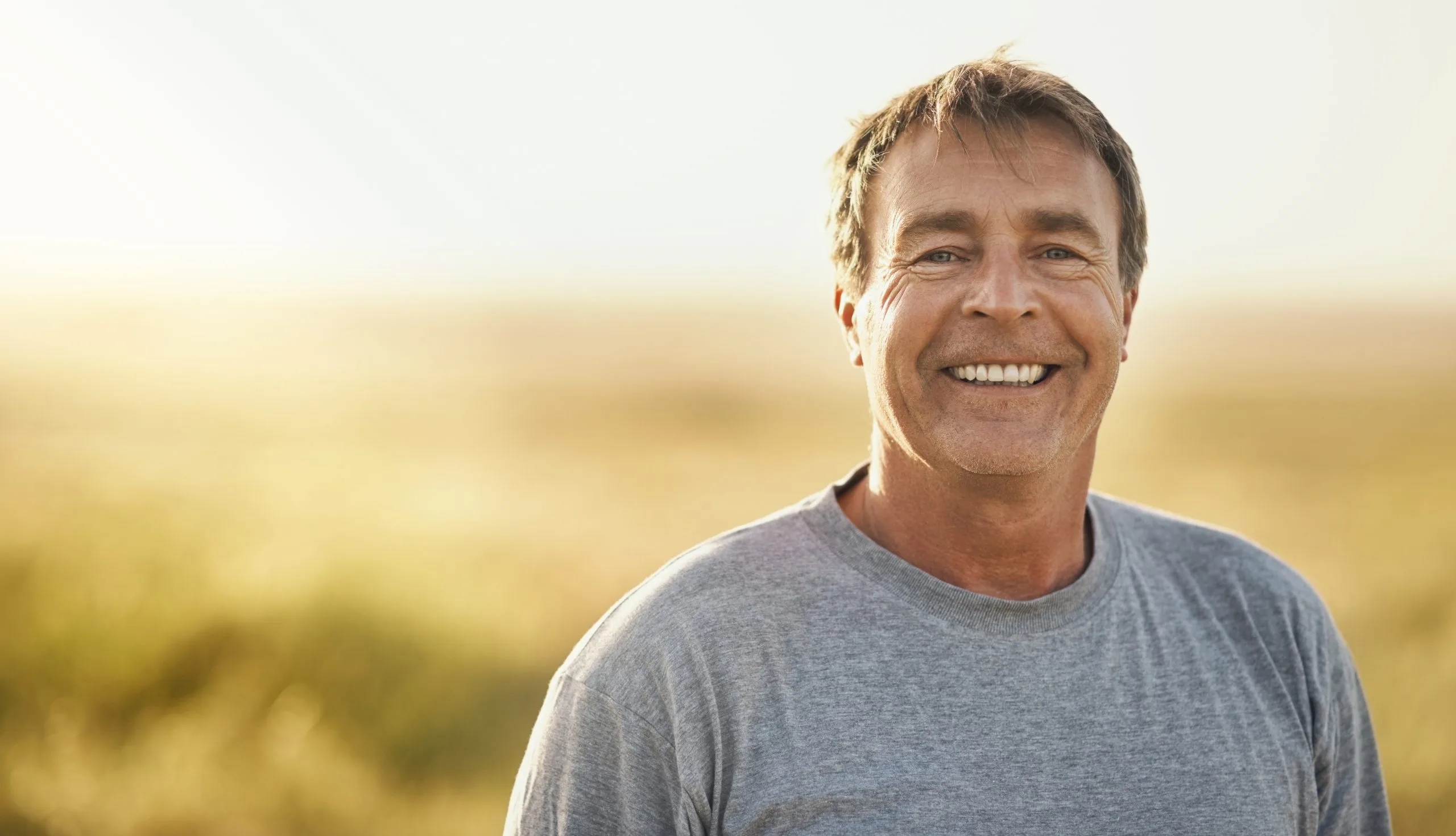 Senior man smiling outdoors in a summer field