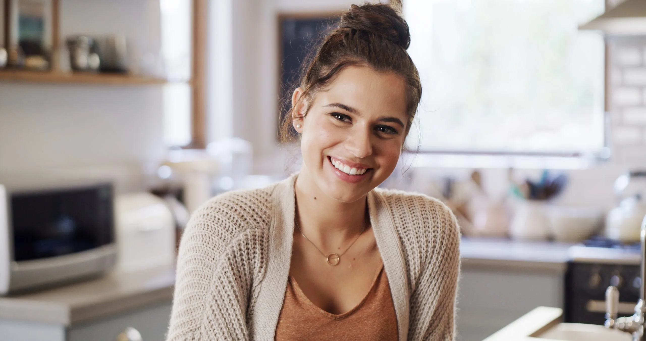 Woman smiling in a bright home kitchen during a relaxation break