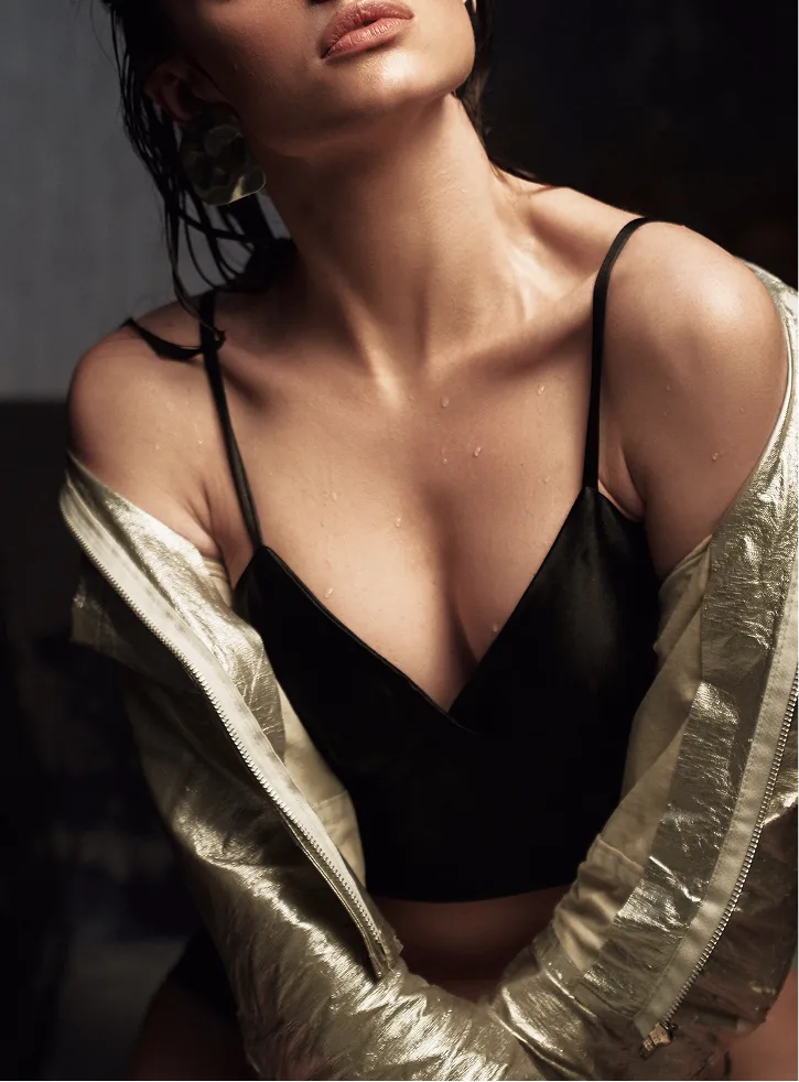 Woman's neck and chest area shown in profile wearing gold metallic jacket