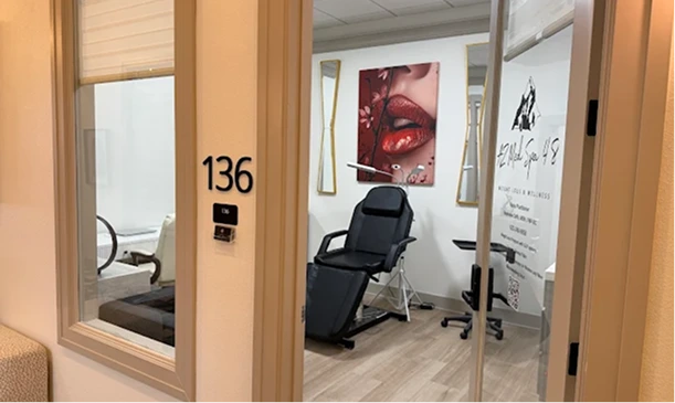 Medical spa treatment room 136 with black reclined chair and lip care artwork on walls