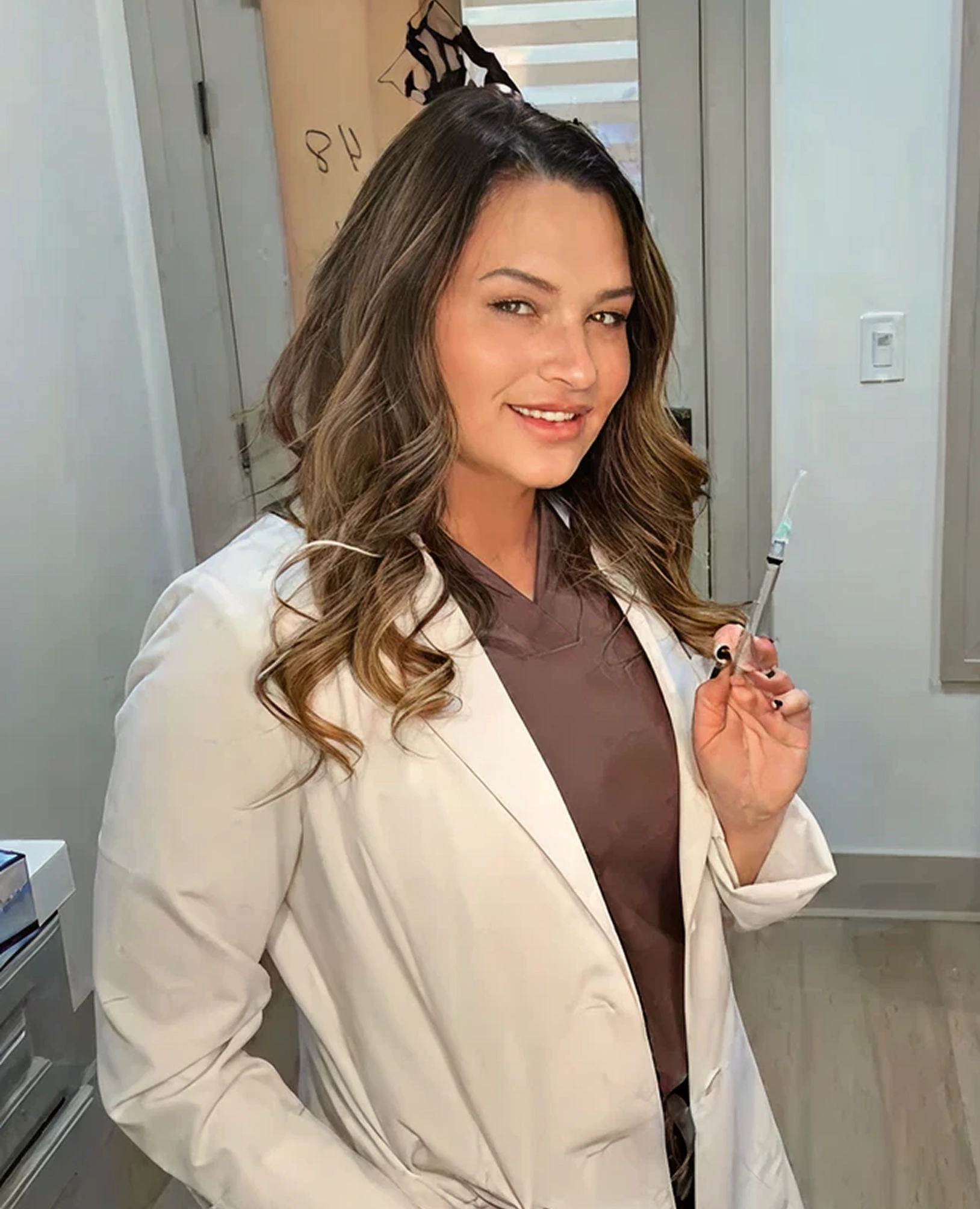 Woman in white coat holding injectable syringe in treatment room