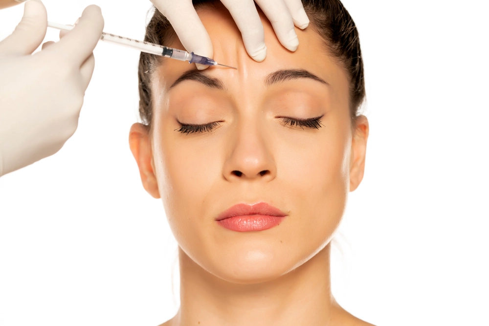 Gloved hands administering injection to forehead area between brows