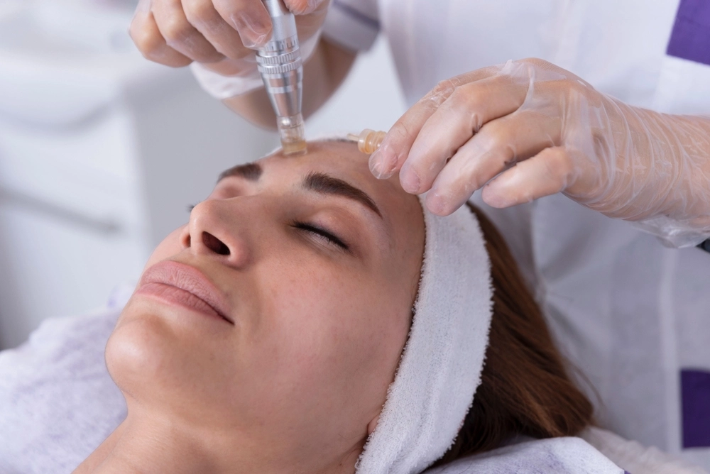Aesthetician applying serum to patient's forehead during facial treatment