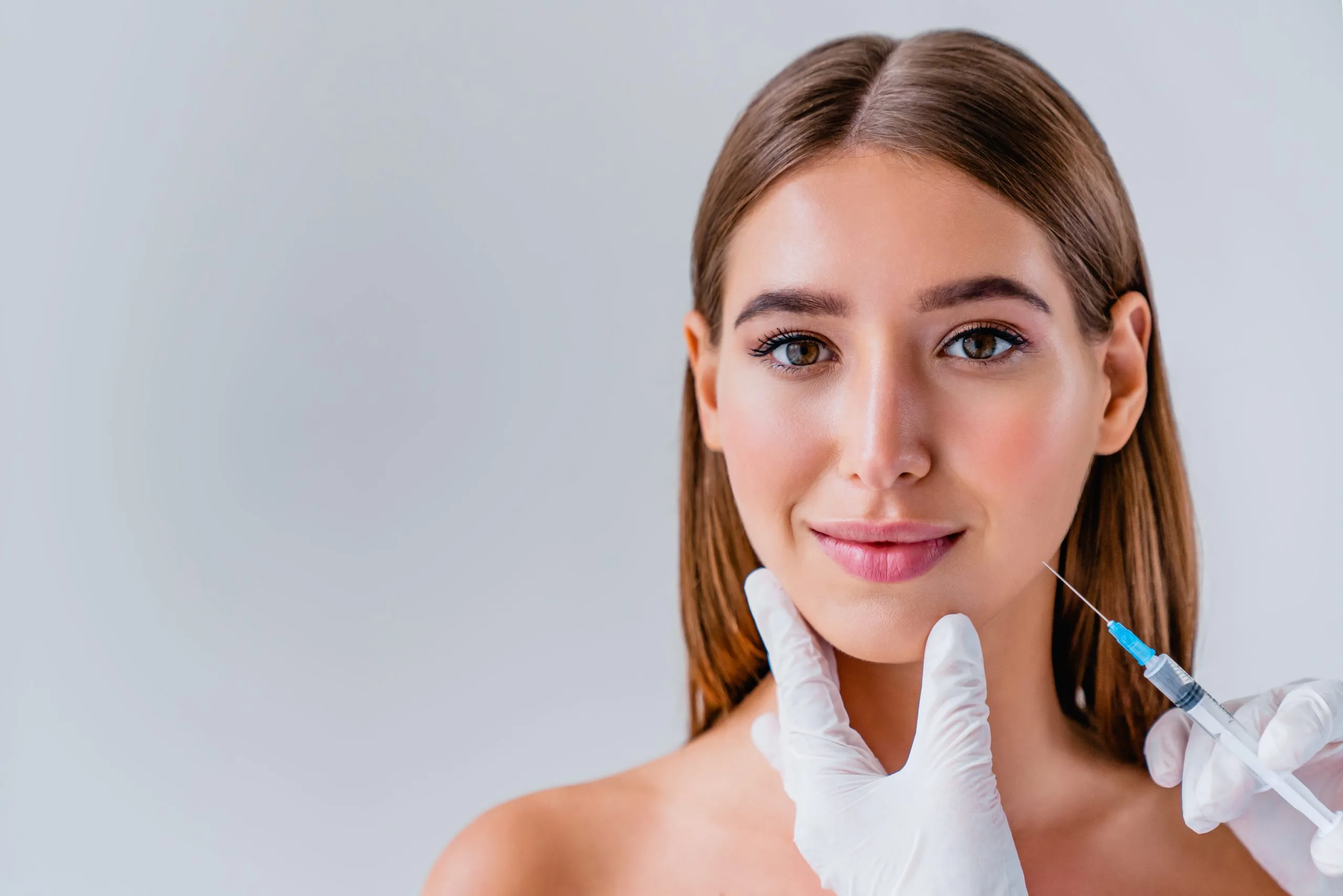 Practitioner injecting dermal filler into patient's cheek area with syringe