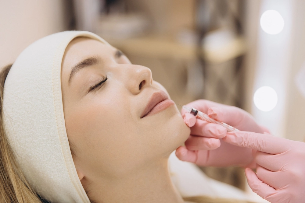 Practitioner applying injectable treatment to patient's chin area during aesthetic procedure