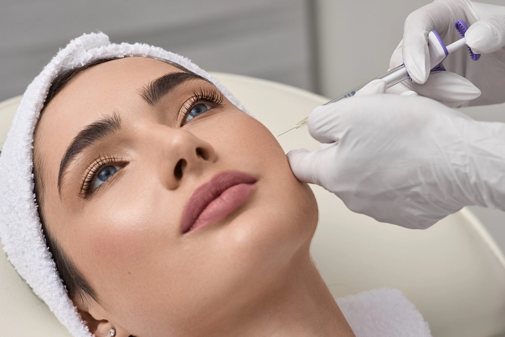 Practitioner using handheld device on patient's forehead during facial treatment