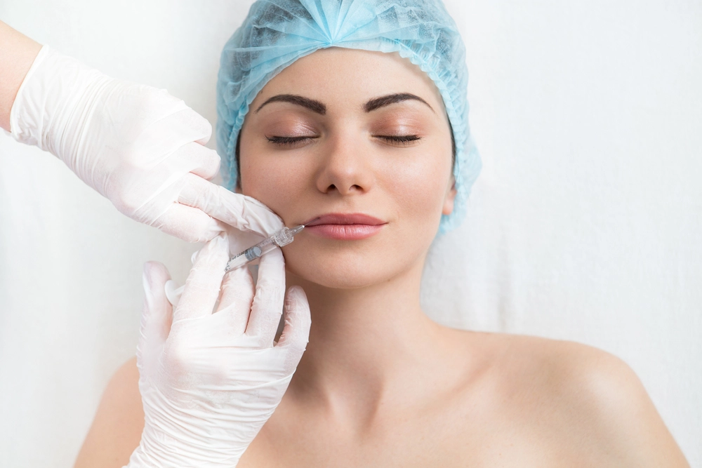 Gloved practitioner performing injectable treatment on patient's cheek