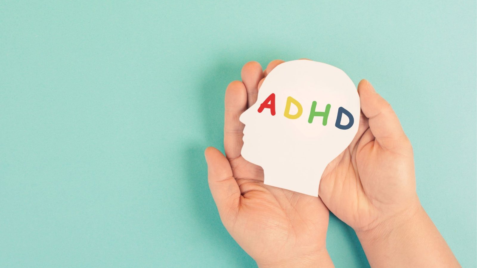 Hands holding a paper head cut-out labeled ADHD