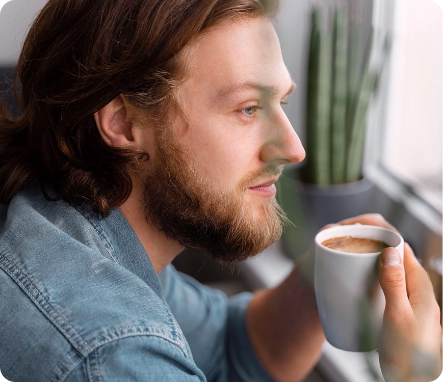 Man holding a coffee mug, looking thoughtful