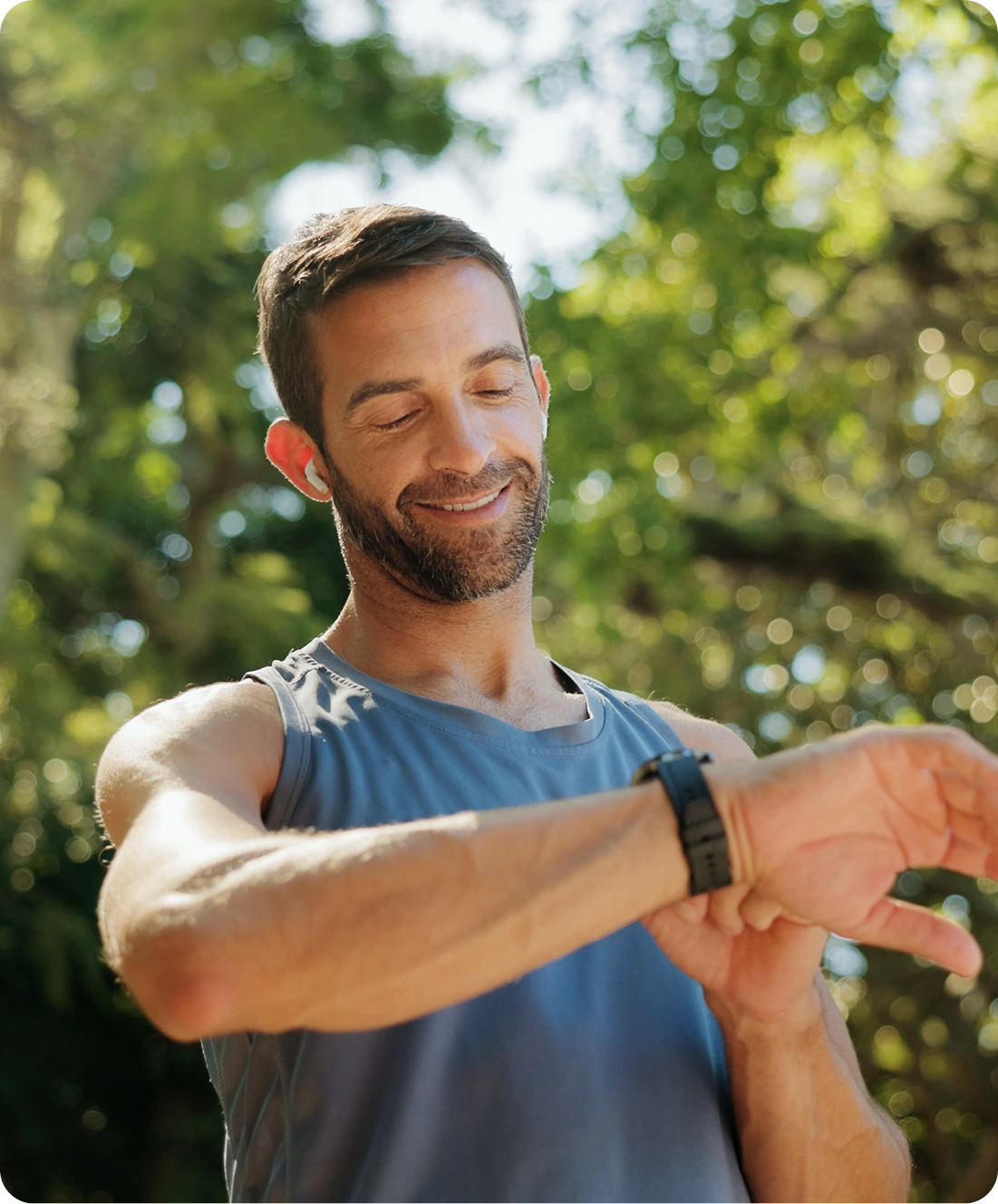 Man stretching his arm outdoors in sunlight among green foliage