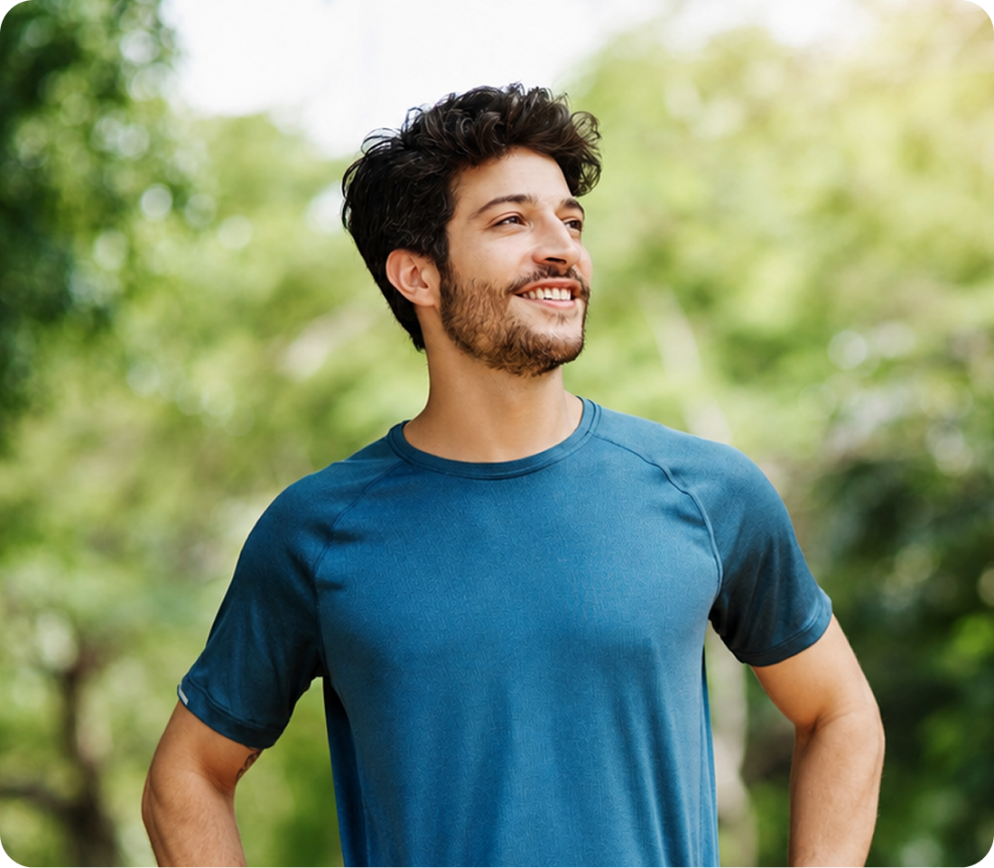 Man smiling outdoors with green foliage background