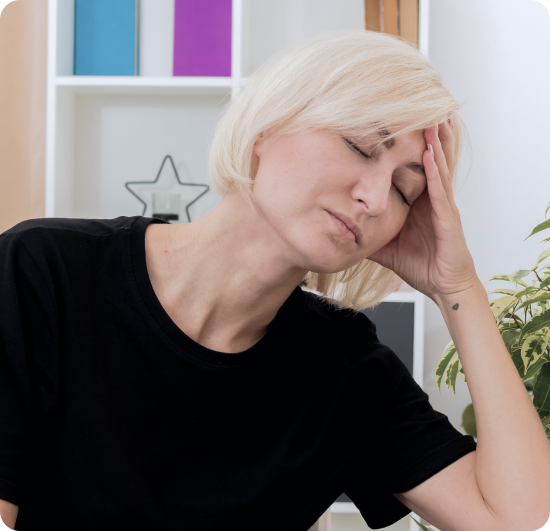 Woman with blonde hair holding her head with her hand, displaying signs of discomfort or pain