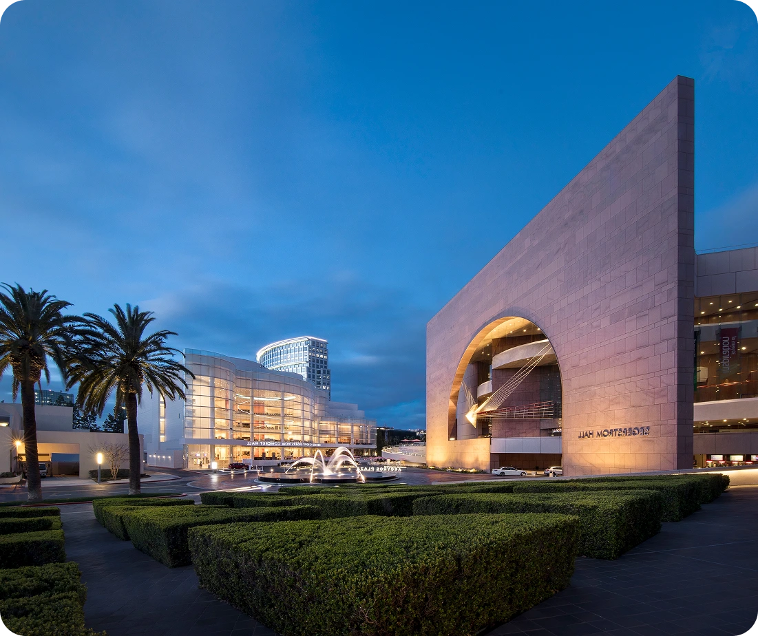 Modern architectural buildings and plaza in Costa Mesa at dusk with palm trees and illuminated structures