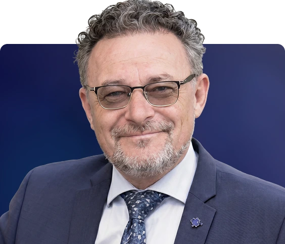 Dr. Robert, wearing glasses and a dark suit with blue tie, smiling at the camera