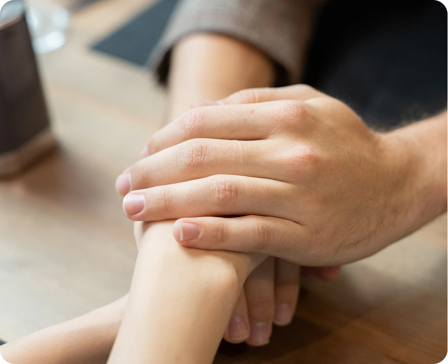 Adult and child stacking hands together in gesture of support and unity