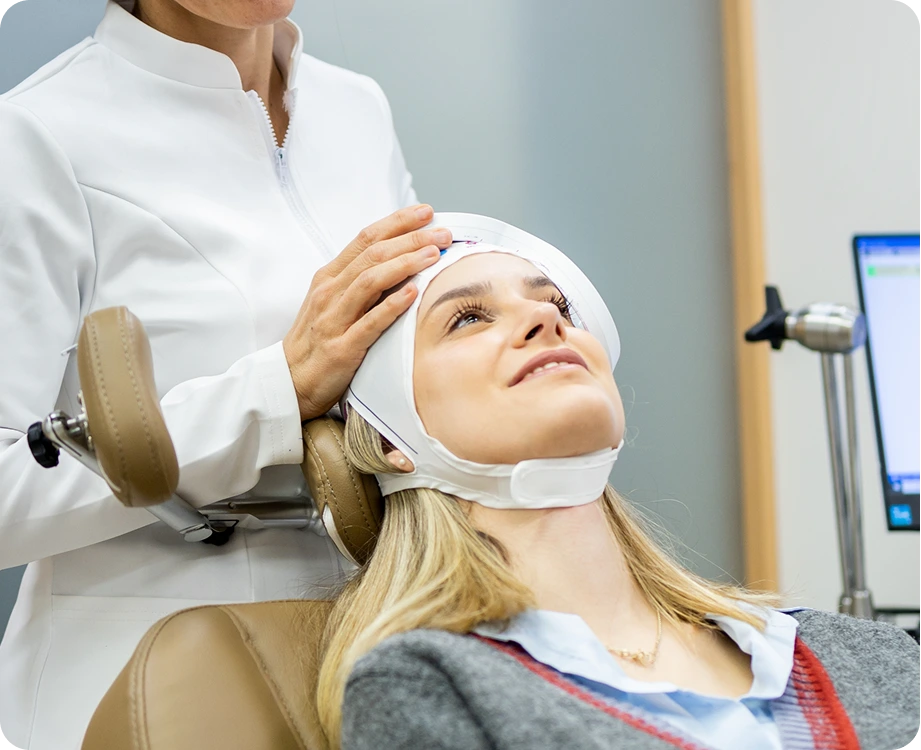 Healthcare provider positioning TMS therapy coil on patient's head during treatment session