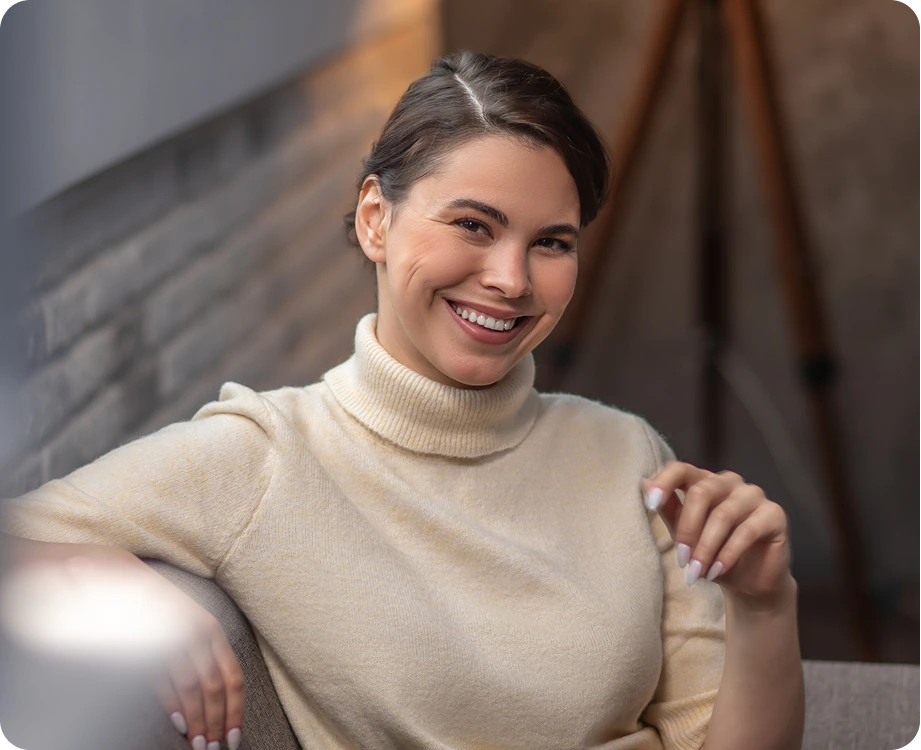 Woman in cream turtleneck smiling while sitting indoors