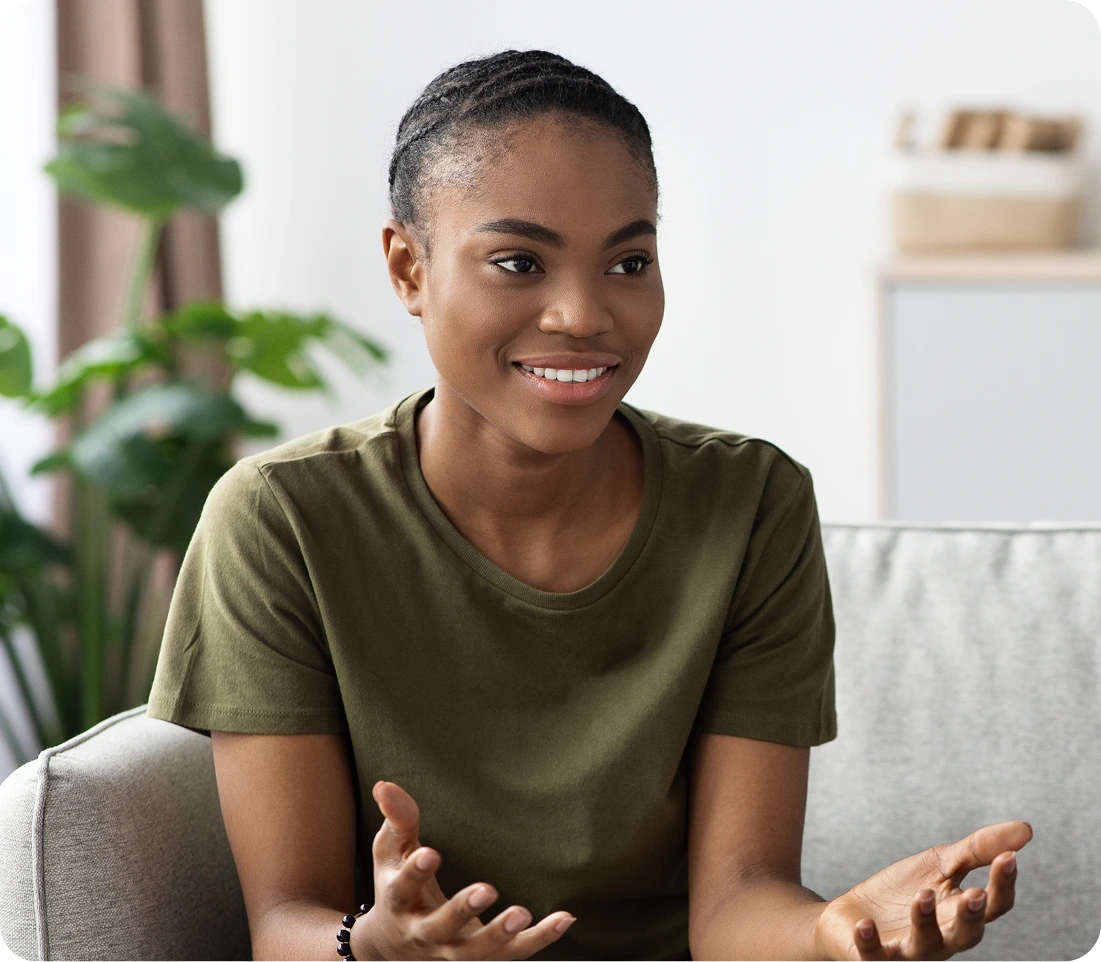 Smiling woman in olive shirt gesturing while speaking in a bright clinical office setting