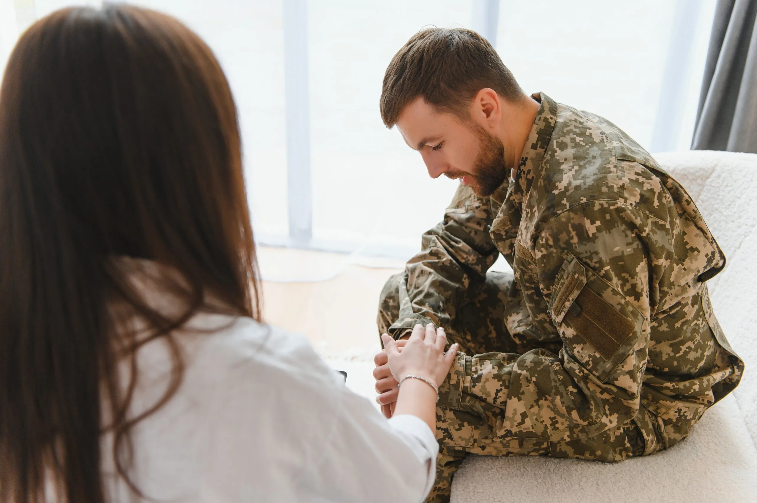Female therapist holding hands with male military service member during counseling session