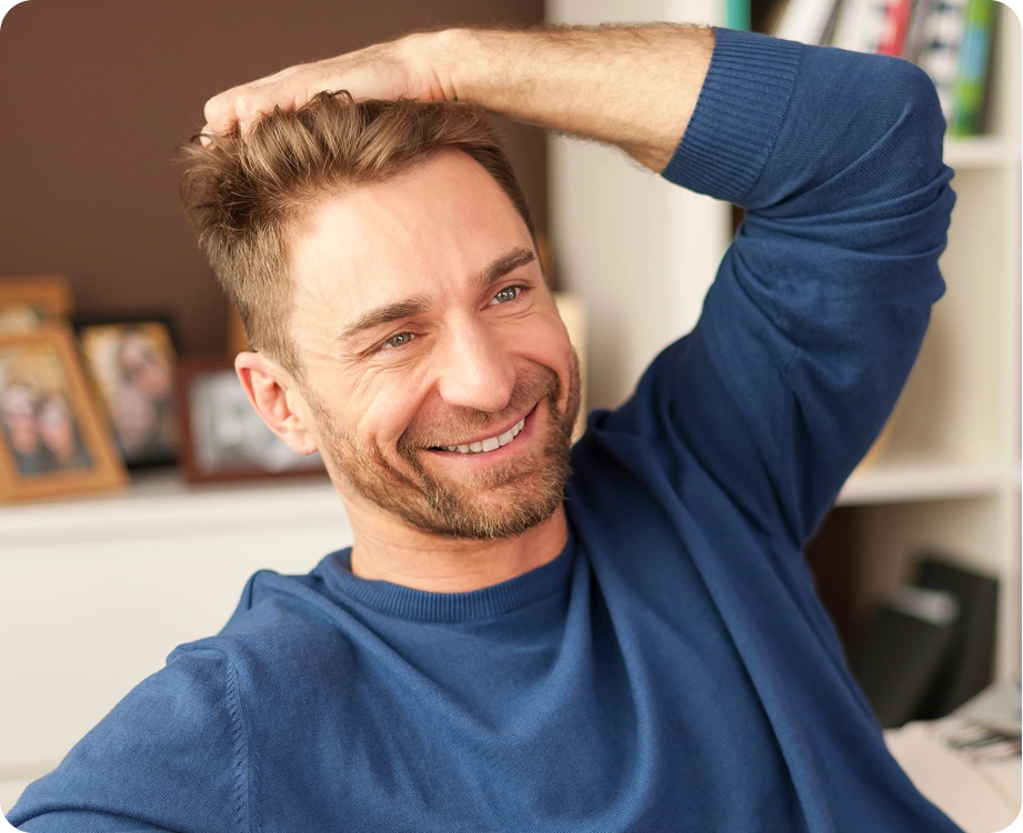 Man smiling with hand raised to his head indoors