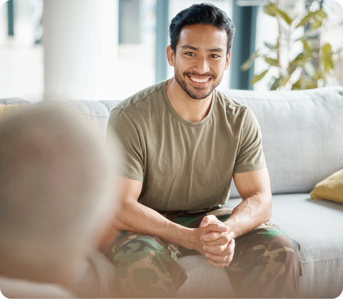 Man sitting on couch smiling during mental health treatment session with therapist