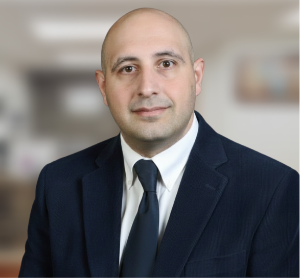 Male dentist in dark suit and tie against blurred dental office background