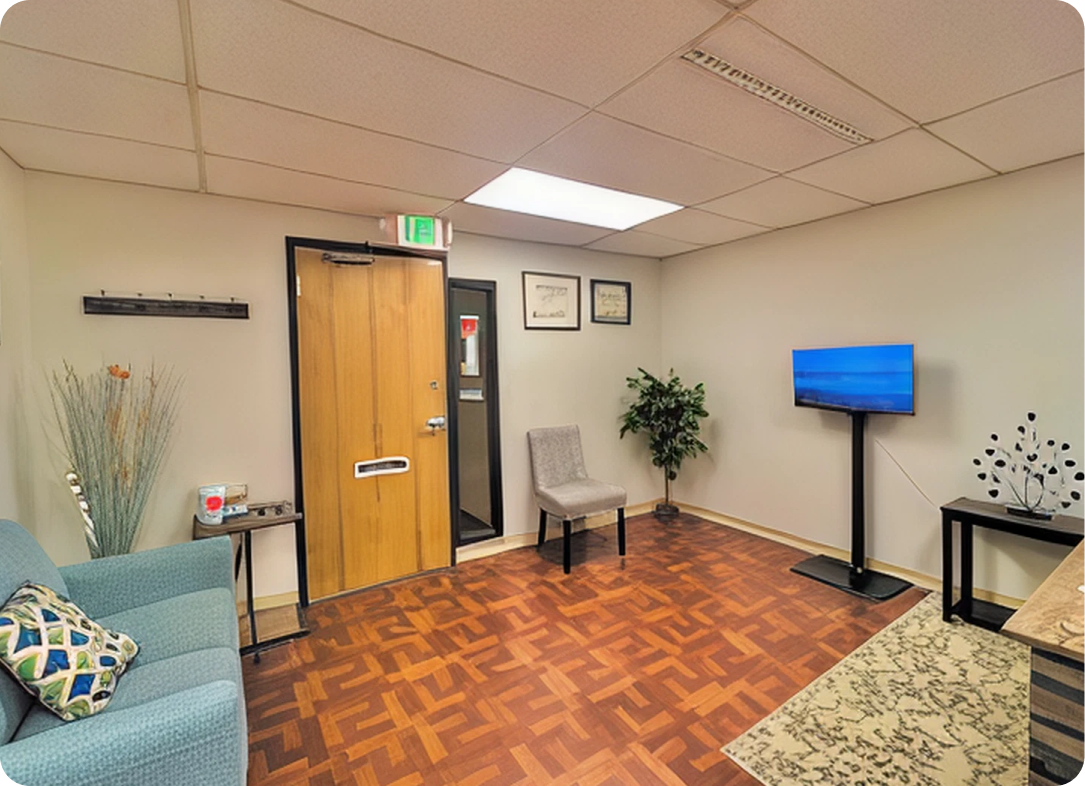 Dental office waiting room with blue upholstered seating, wooden door, and mounted television