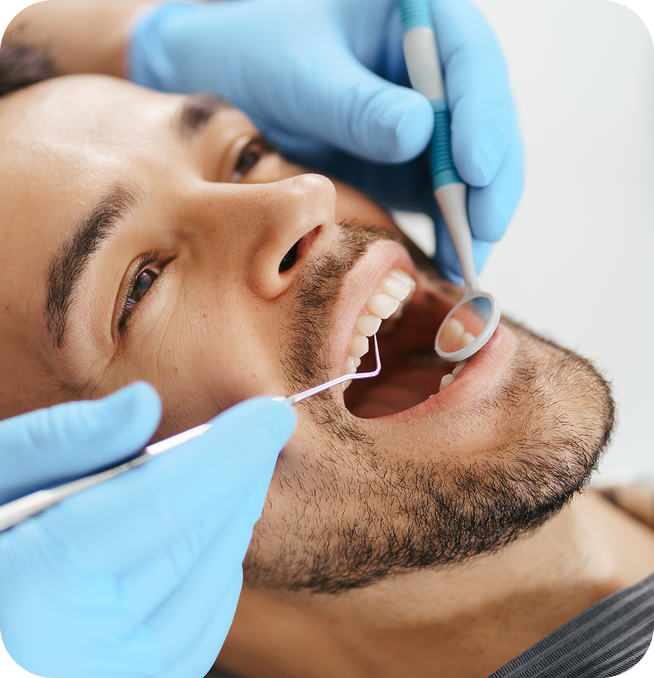 Dentist examining male patient's teeth with mirror and dental tools