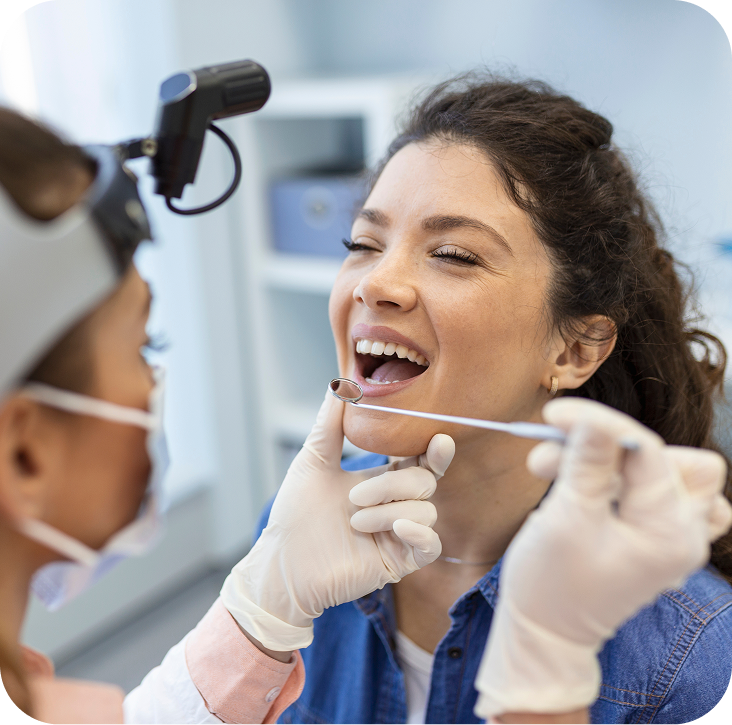 Dentist using intraoral camera to examine female patient's teeth in clinical setting