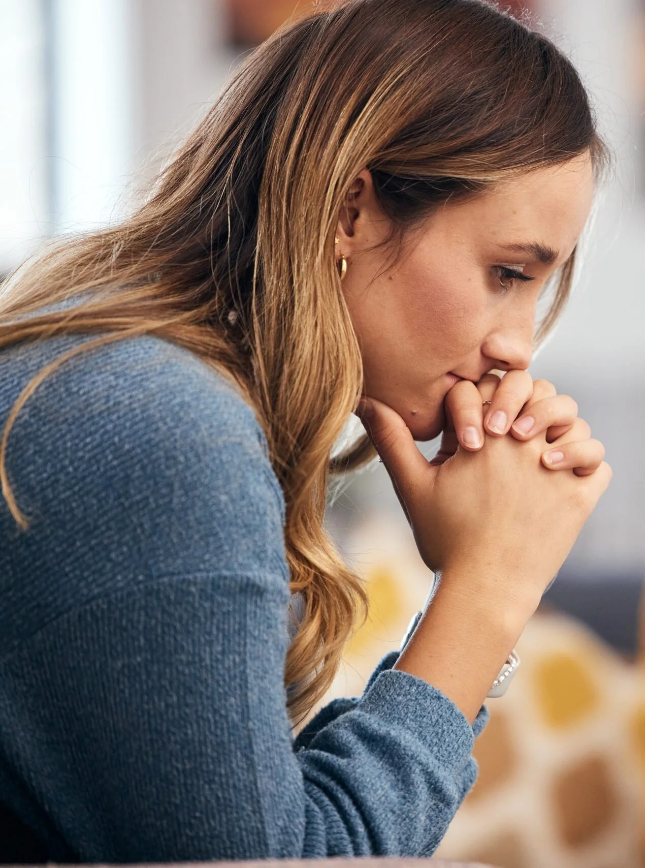 Woman resting her chin on her clasped hands, deep in thought