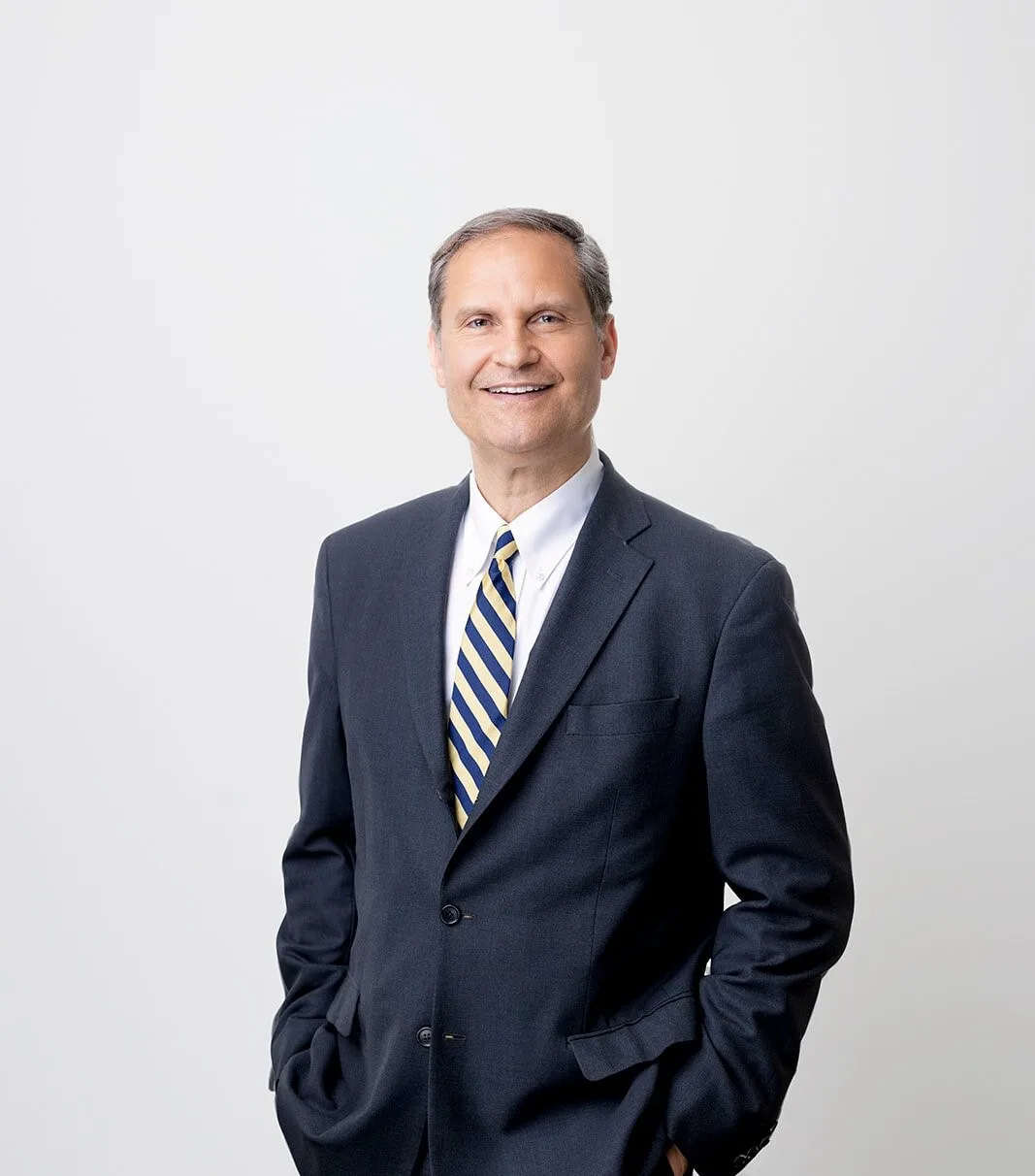 Professional headshot of male plastic surgeon in dark blazer and blue striped tie