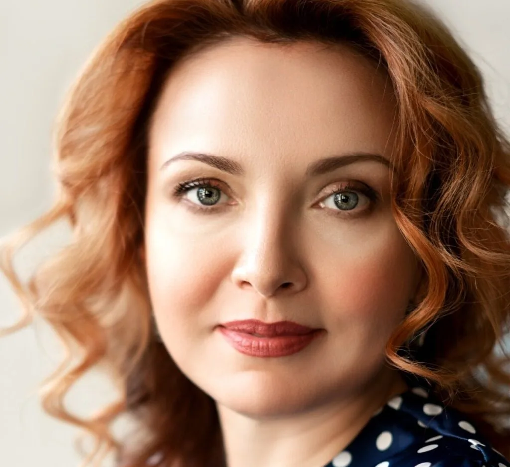 Woman with reddish-brown wavy hair looking directly at camera in post-operative period