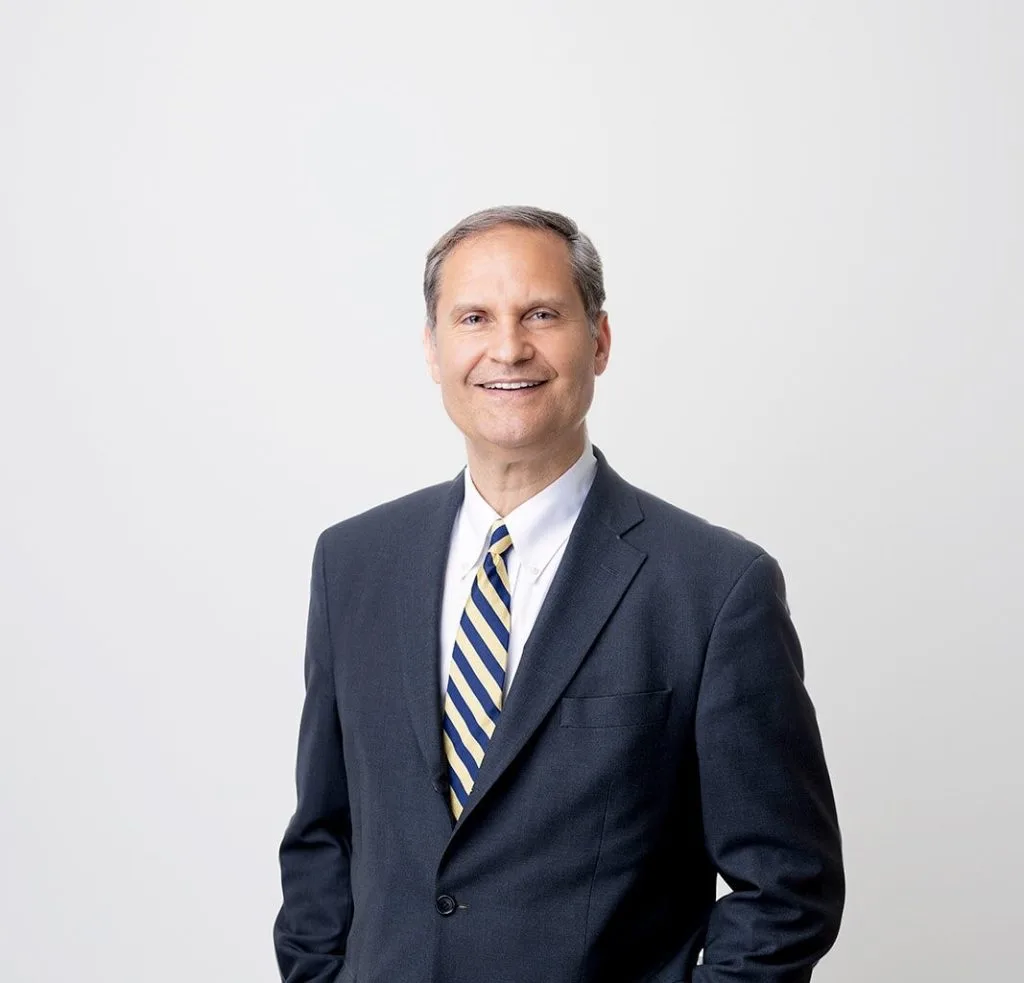 Dr. Joseph F in dark suit with blue and white striped tie