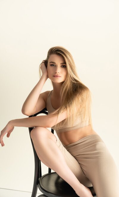 Woman in beige sports bra and briefs posing seated against neutral background