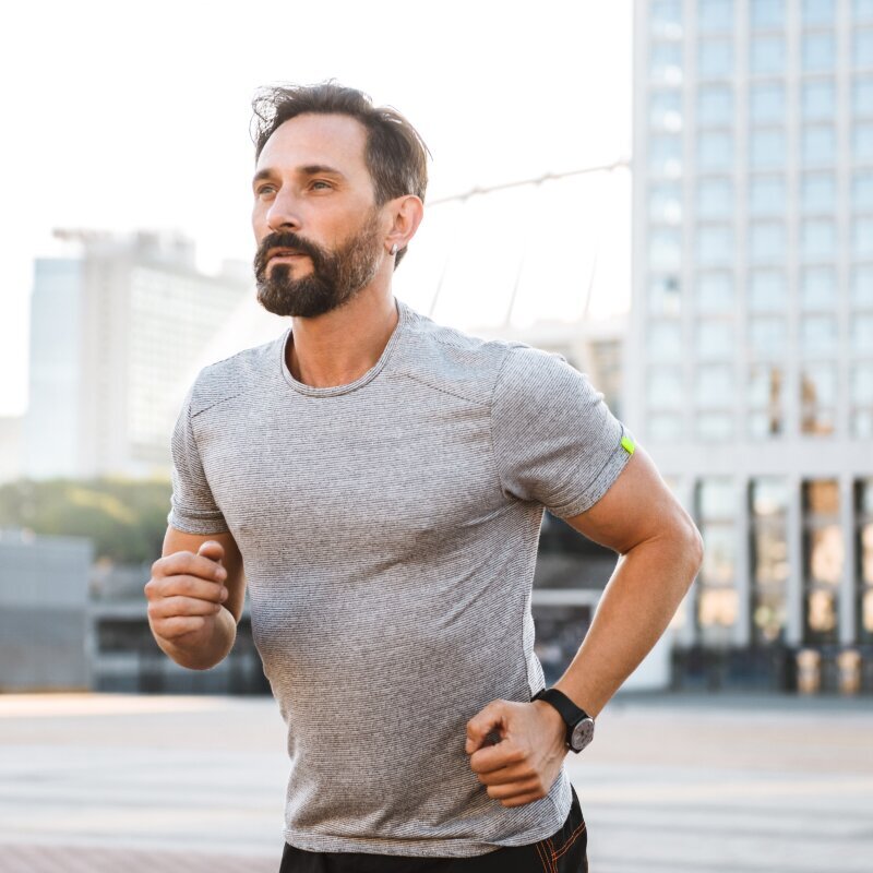 Man jogging on urban rooftop with city skyline in background