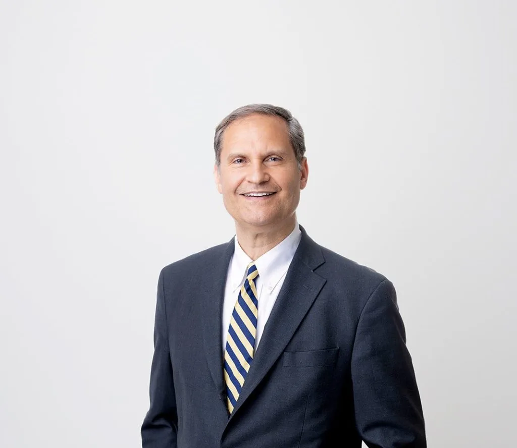Dr. Joseph F. Capella, plastic surgeon, in professional headshot wearing dark blazer and striped tie