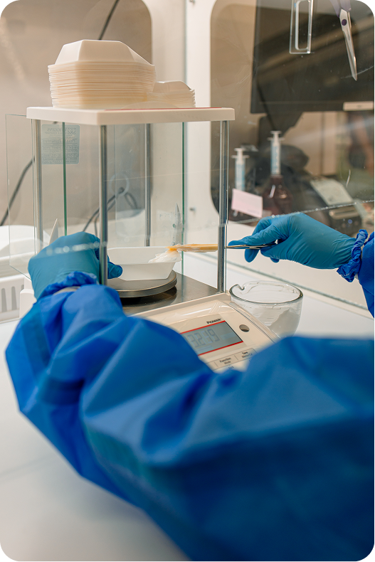 Pharmacist in blue gloves preparing medication using a compounding device in laboratory setting