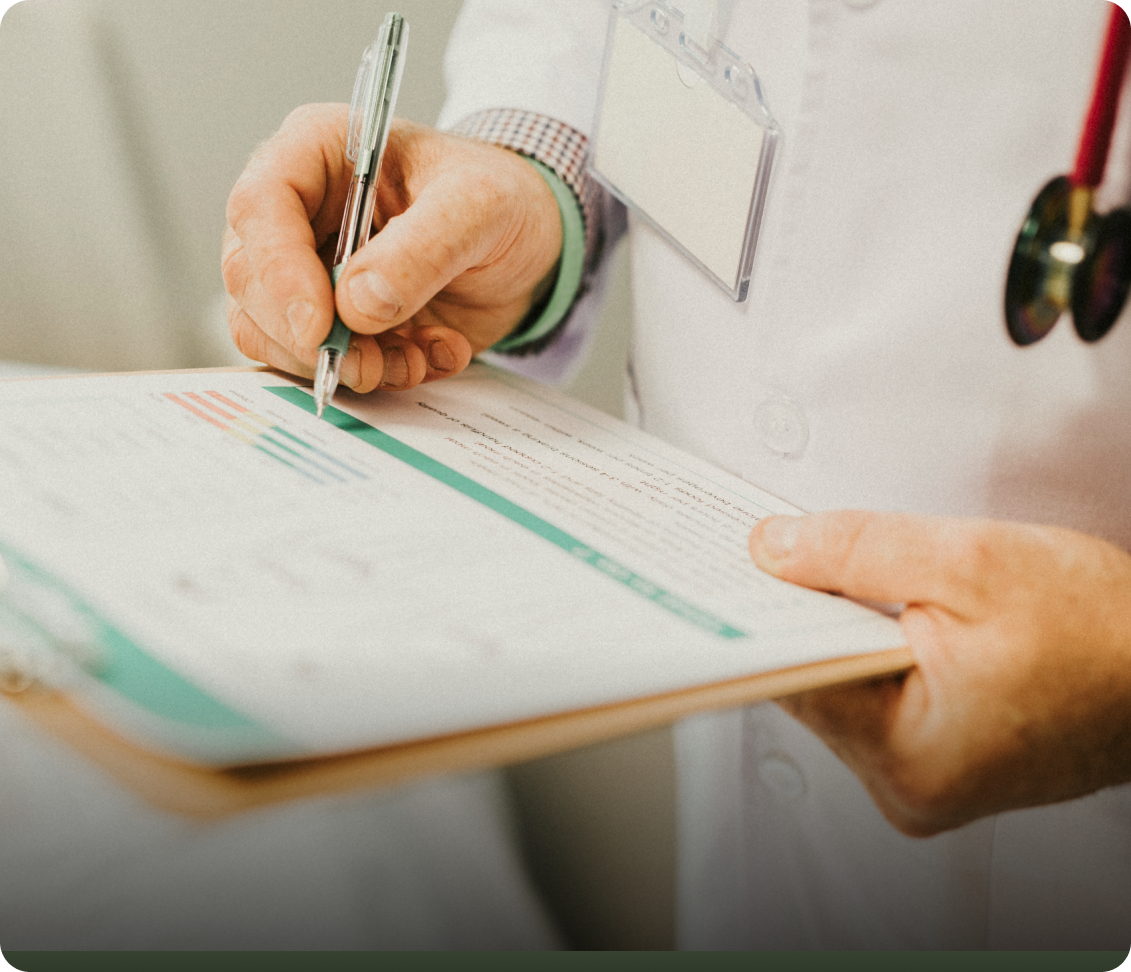 Clinician's hands reviewing and marking a patient document on a clipboard during a consultation