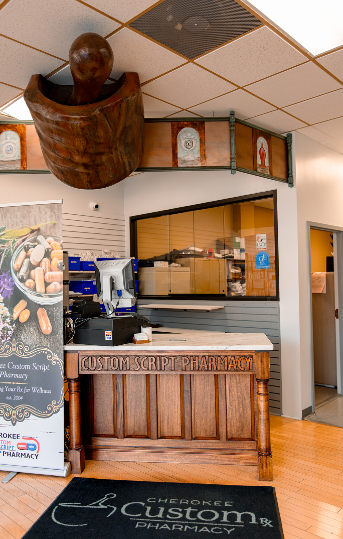 Cherokee Custom Script Pharmacy interior showing counter, decorative wooden mortar and pestle, and shelving