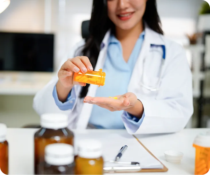 Healthcare provider holding orange prescription bottle with medications displayed