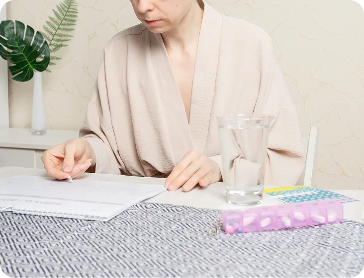 Patient reviewing medication instructions while sitting at table with water glass and pill organizer