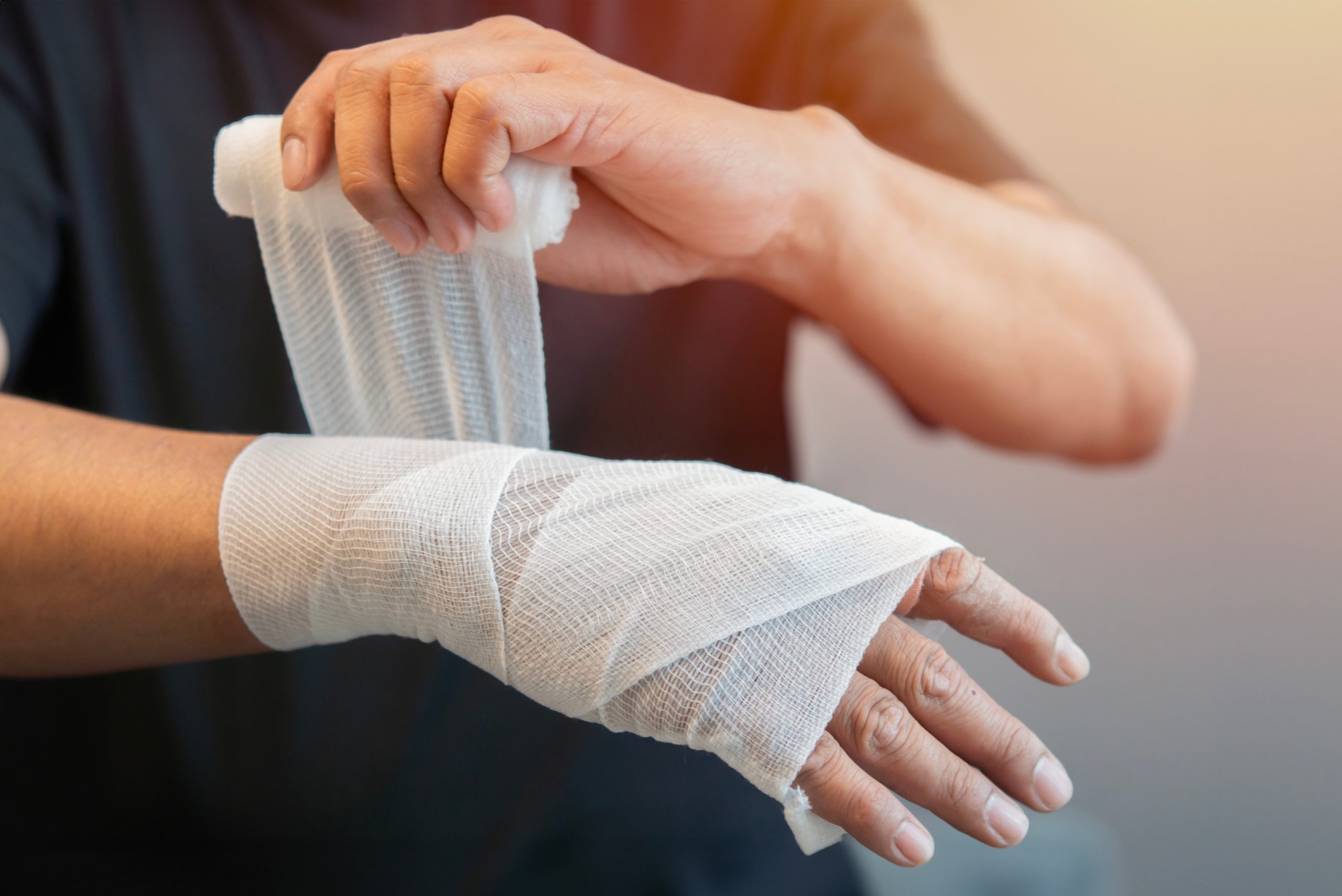 Person wrapping gauze bandage around their wrist and hand