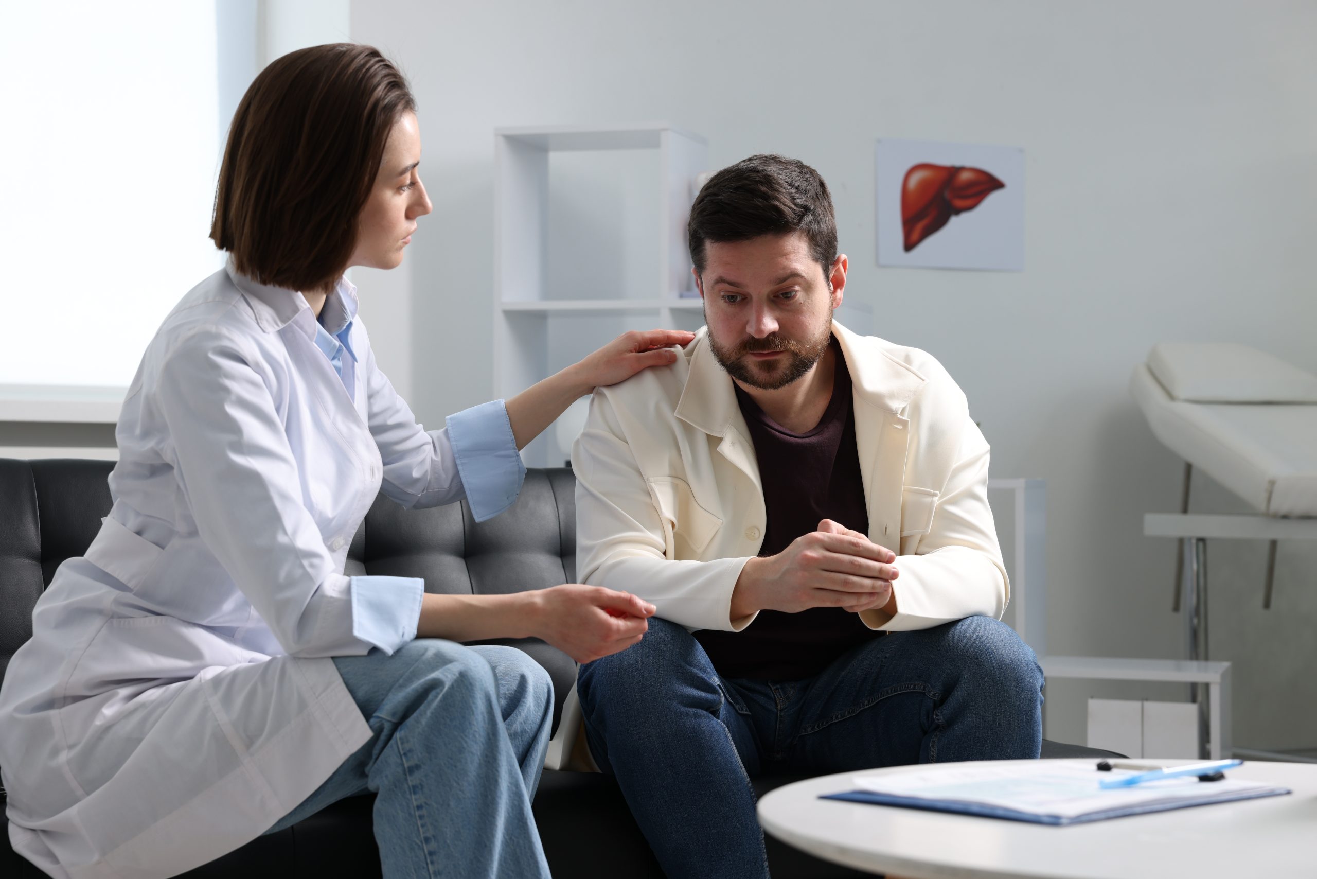 Healthcare provider in white coat discussing treatment with male patient seated in clinical office