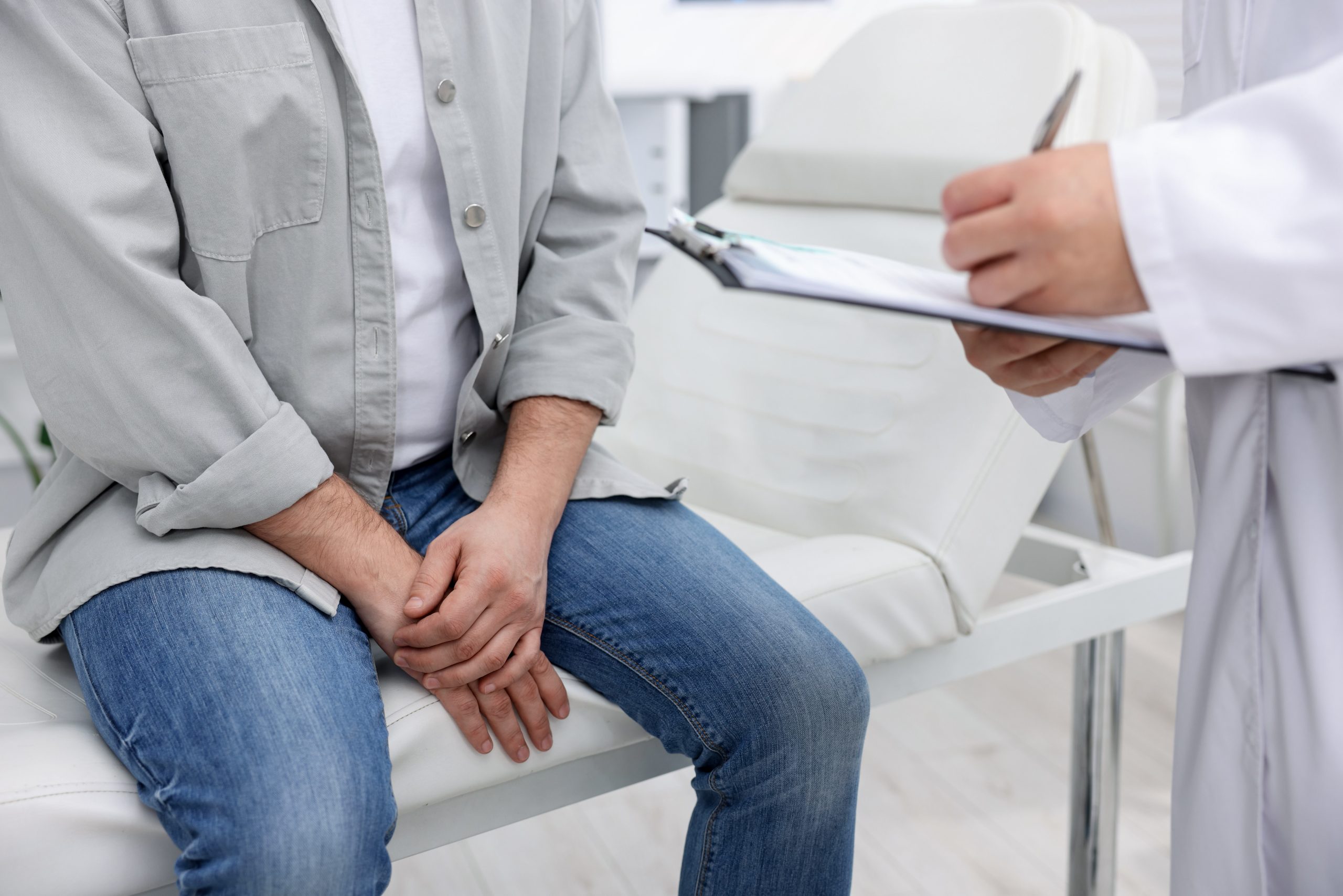 Healthcare provider holding clipboard reviewing patient information with seated man