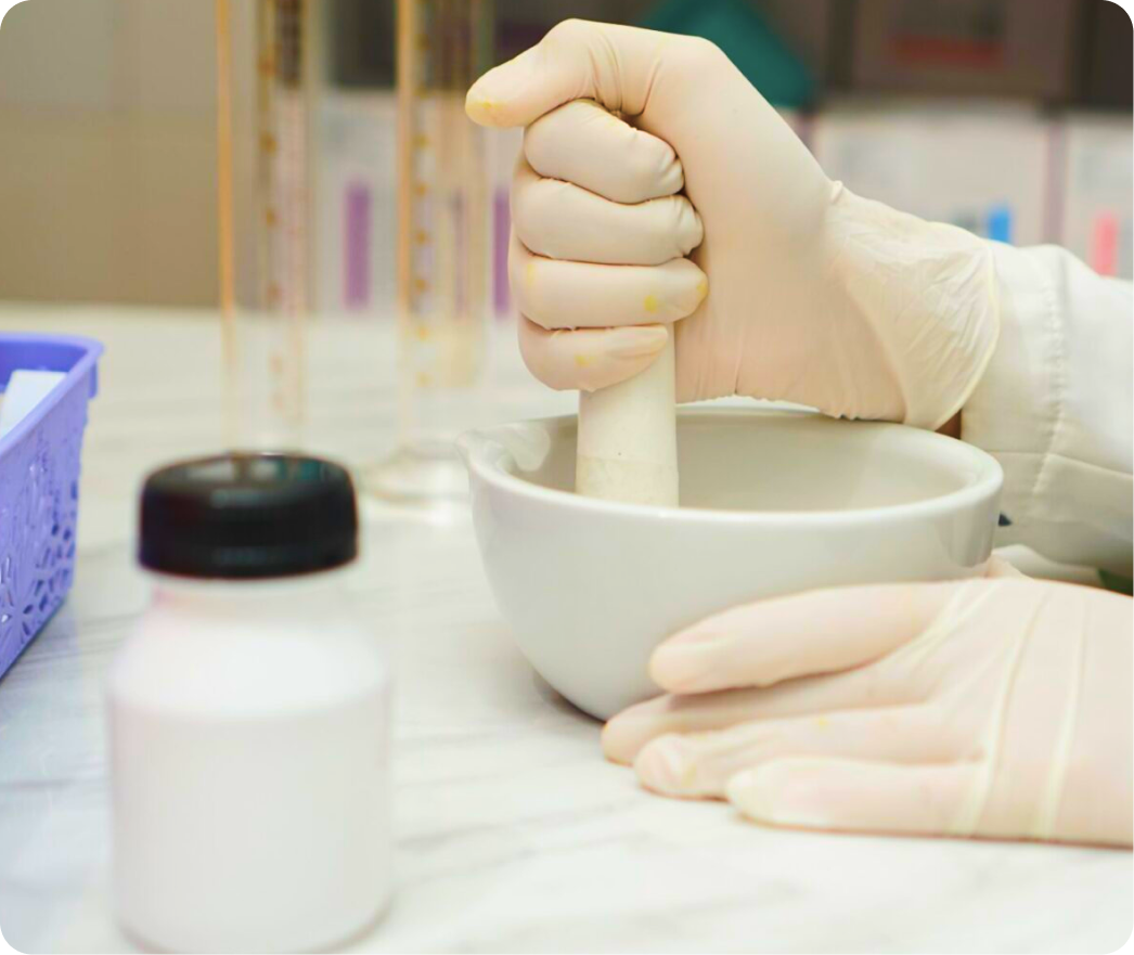 Pharmacist in latex gloves mixing compound in mortar at compounding pharmacy counter