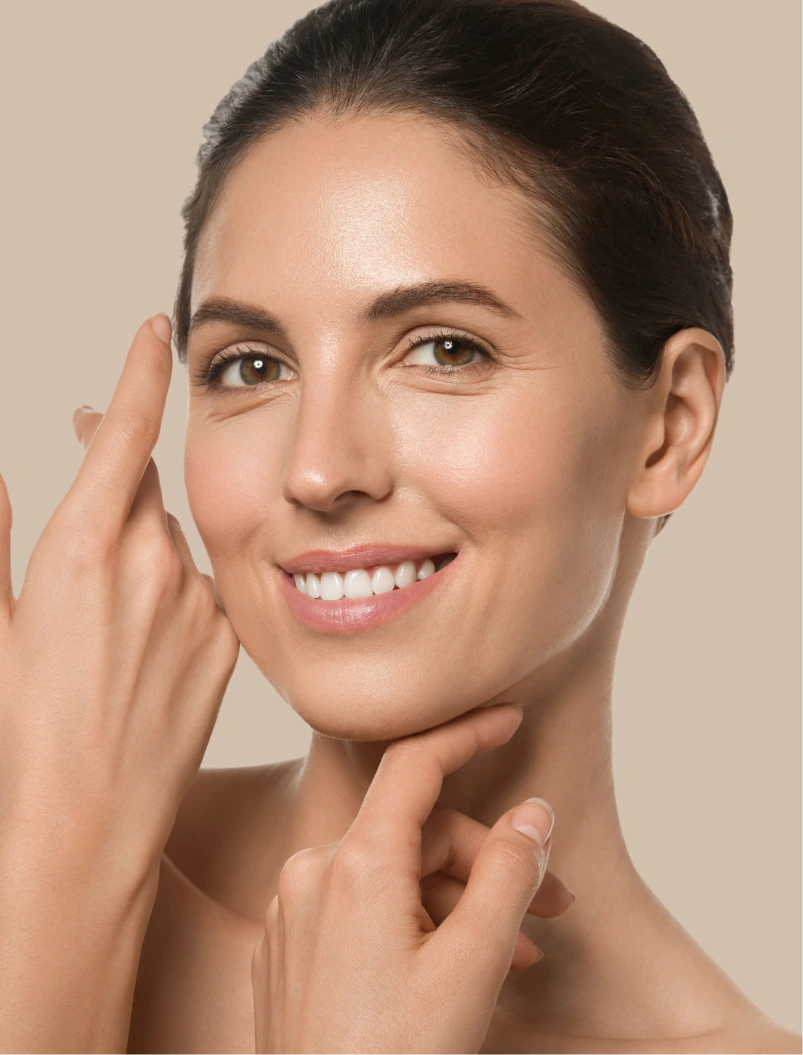 Woman touching her face with both hands, smiling against a beige background