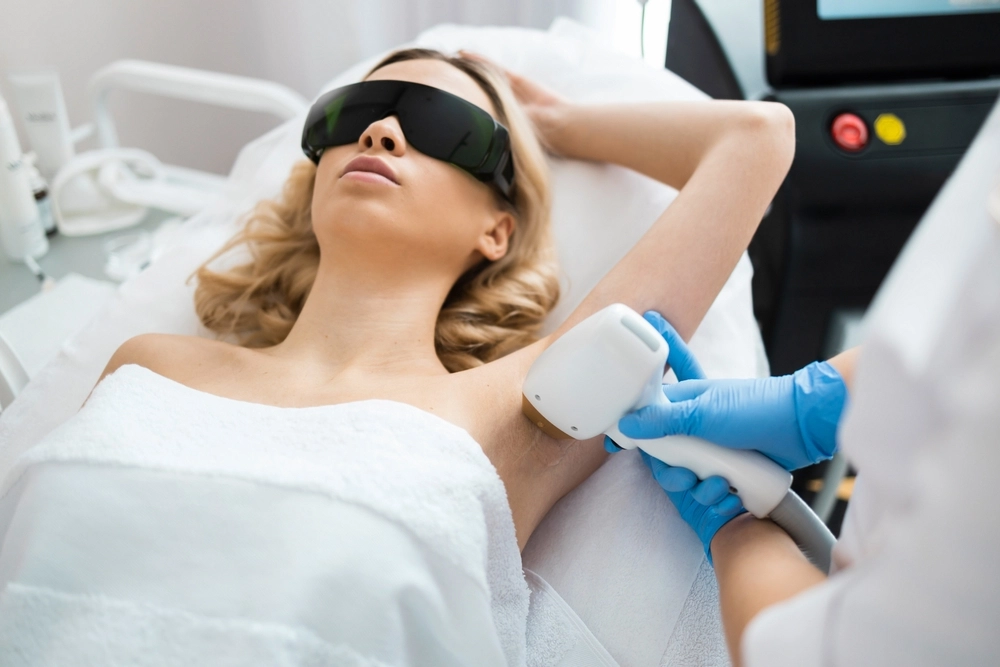 Patient wearing protective eyewear receives laser treatment on chest from provider in medical office